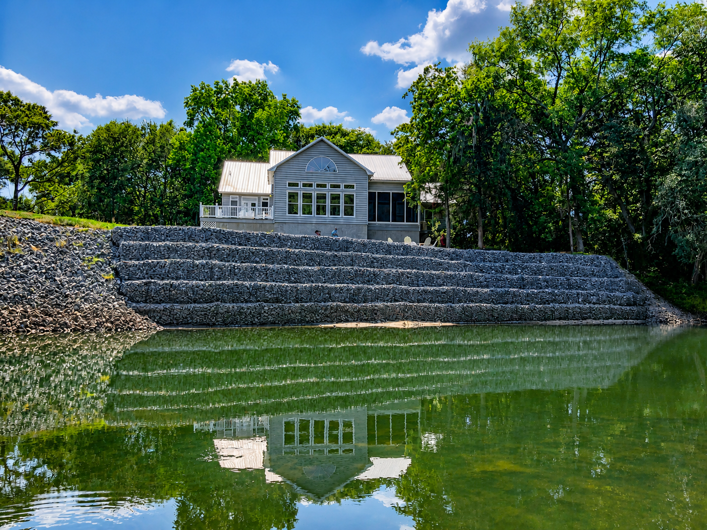 Waterfront home with gabion retaining wall and pond